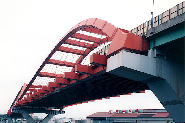 Nada Bridge: red steel arch bridge carrying an elevated expressway above an urban riverside district