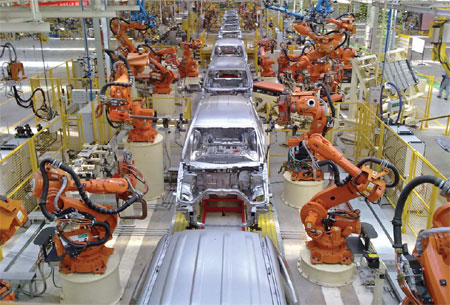 Car body-in-white assembly line with orange industrial robots, illustrating automation in automotive manufacturing