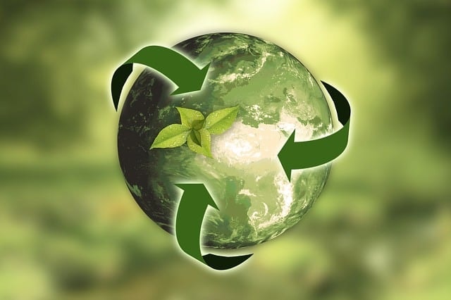 Globe circled by green recycling arrows with a leaf sprout, symbolizing sustainable manufacturing