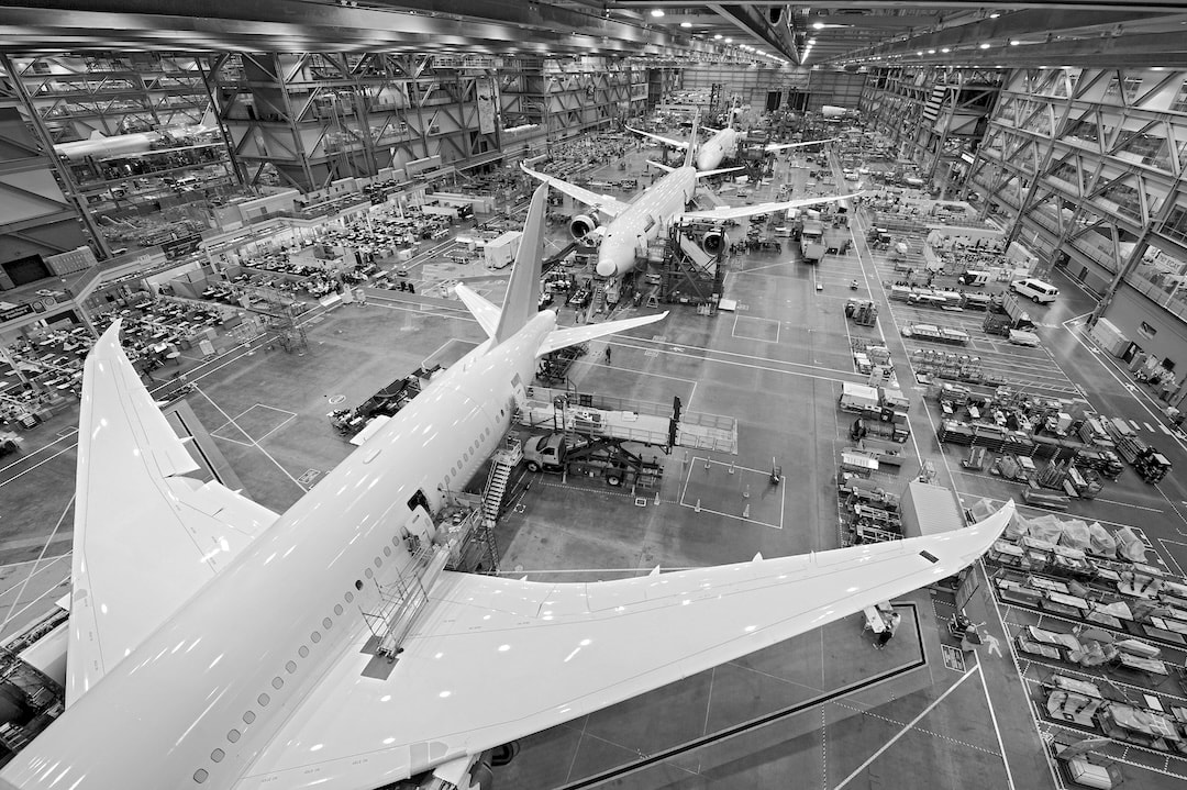 Black-and-white view of wide-body airliners in a final assembly hall, illustrating large aerospace programs