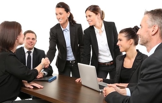 Business team meeting around a table with a handshake, illustrating cross-department collaboration