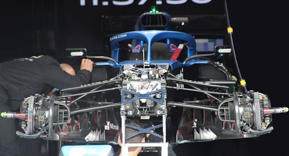Front axle assembly of a Formula 1 car with the bodywork removed, showing the brake duct and disc