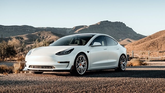 White electric sedan parked in a desert landscape, context for cabin preconditioning while plugged in